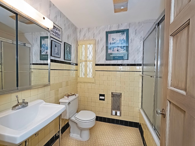 full bathroom with tile floors, combined bath / shower with glass door, toilet, and tile walls