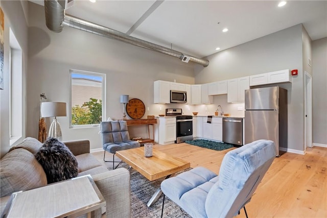 living room featuring sink, light hardwood / wood-style floors, and a high ceiling