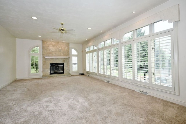 unfurnished living room with light carpet, ceiling fan, a healthy amount of sunlight, and a fireplace