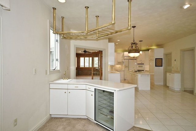 kitchen featuring kitchen peninsula, wine cooler, white cabinets, and decorative light fixtures