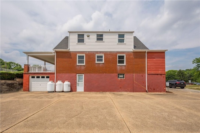 exterior space with a garage, roof with shingles, and brick siding