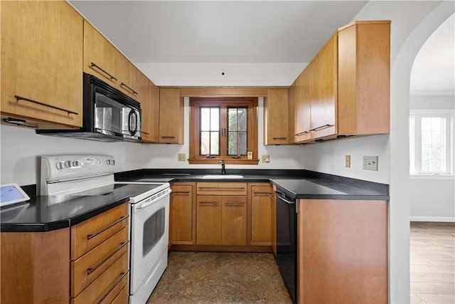 kitchen featuring dark countertops, brown cabinets, a sink, and black appliances