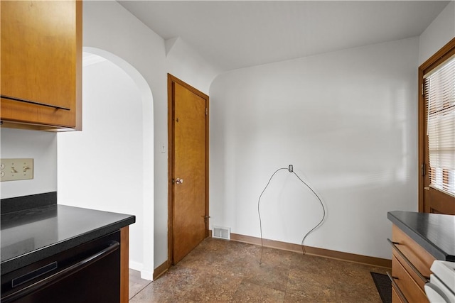 kitchen with dark countertops, plenty of natural light, arched walkways, and baseboards