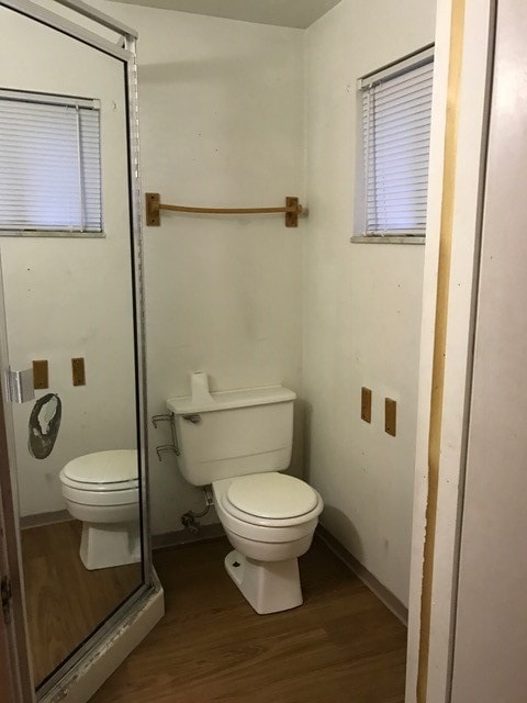 bathroom with a shower with shower door, hardwood / wood-style flooring, and toilet