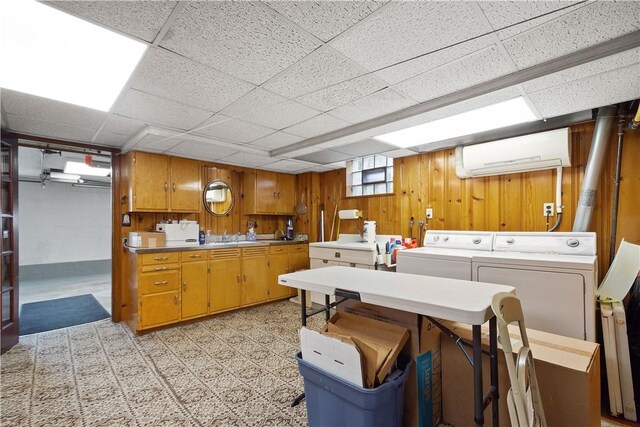 laundry area featuring washing machine and clothes dryer, sink, a wall mounted AC, wood walls, and light carpet