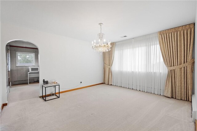 carpeted spare room with a baseboard radiator and an inviting chandelier