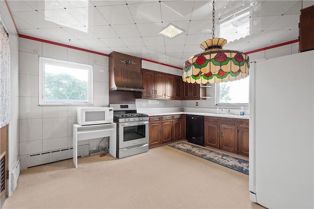 kitchen featuring wall chimney range hood, white appliances, a wealth of natural light, and light colored carpet