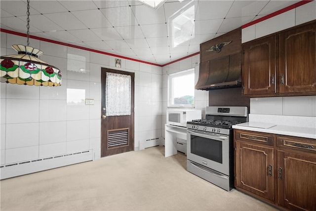 kitchen featuring dark brown cabinetry, gas range, tile walls, and a baseboard radiator