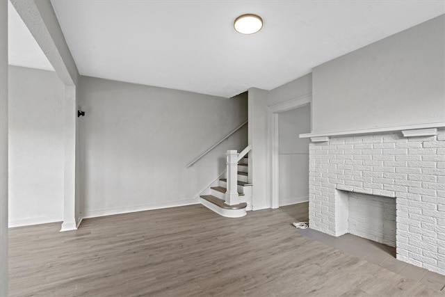 unfurnished living room featuring hardwood / wood-style flooring and a brick fireplace