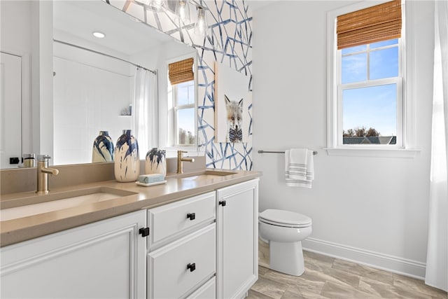 bathroom featuring dual bowl vanity and toilet