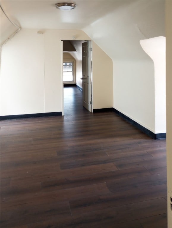 bonus room with dark wood-type flooring and lofted ceiling