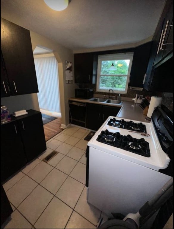 kitchen featuring light tile patterned flooring, gas range gas stove, and sink