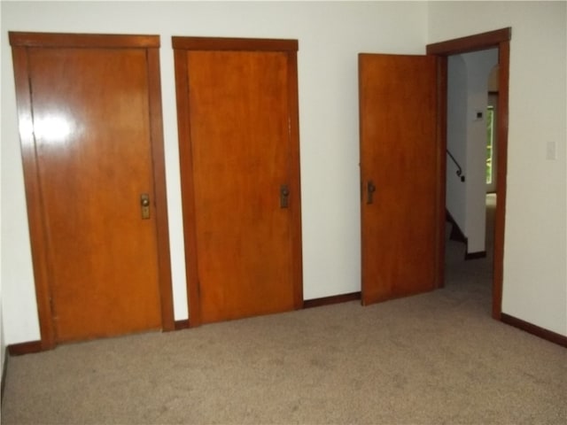 unfurnished bedroom featuring two closets and carpet floors