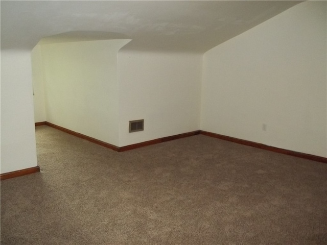 spare room with dark colored carpet and lofted ceiling