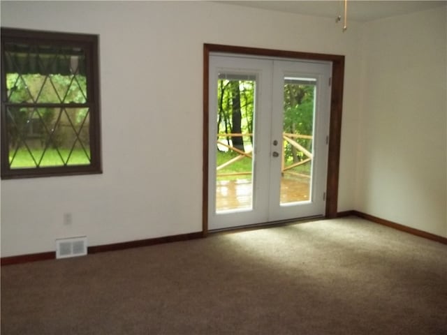 carpeted empty room with a wealth of natural light and french doors