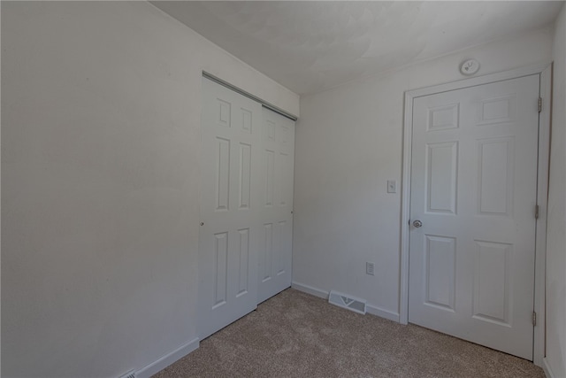 unfurnished bedroom with light colored carpet and a closet