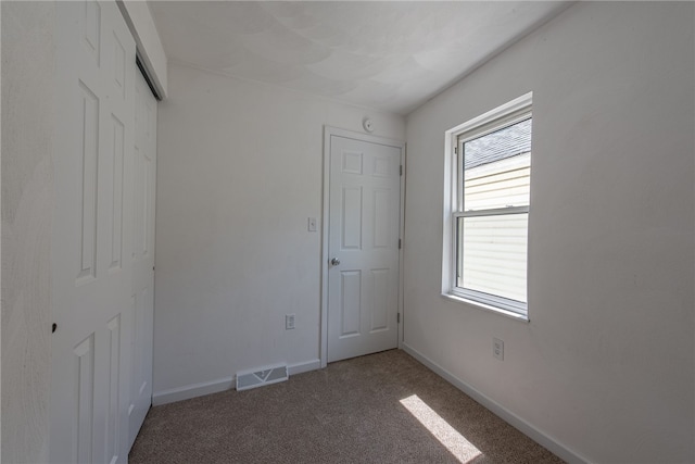 unfurnished bedroom featuring a closet, carpet floors, and multiple windows