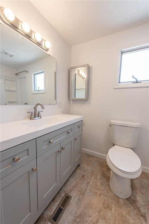 bathroom with a wealth of natural light, vanity, and toilet