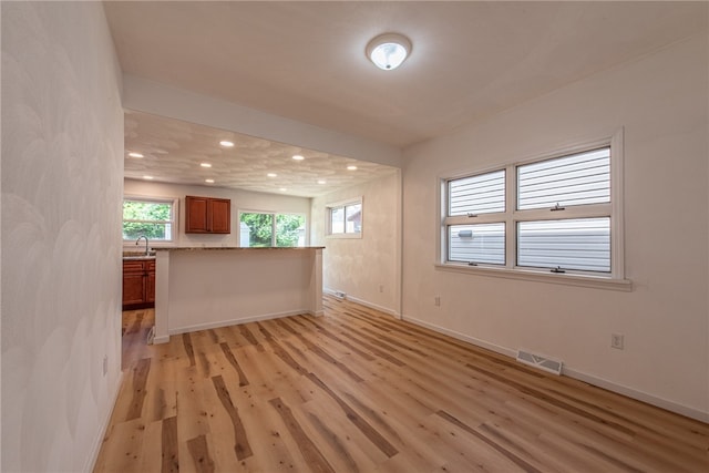 unfurnished living room featuring sink and light hardwood / wood-style floors