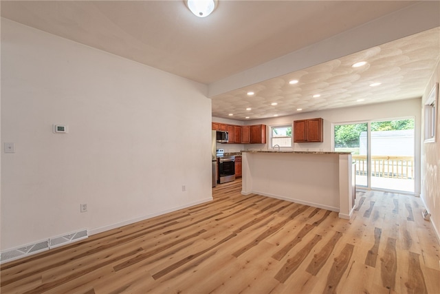 kitchen featuring light wood-type flooring, light stone counters, and stainless steel appliances