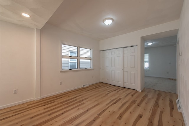 unfurnished bedroom featuring multiple windows, a closet, and light hardwood / wood-style floors