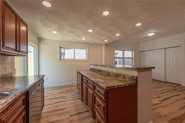 kitchen with a healthy amount of sunlight, light hardwood / wood-style flooring, stainless steel dishwasher, and a kitchen island