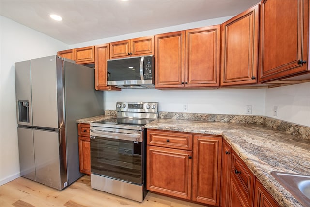 kitchen featuring light hardwood / wood-style flooring, light stone counters, and stainless steel appliances