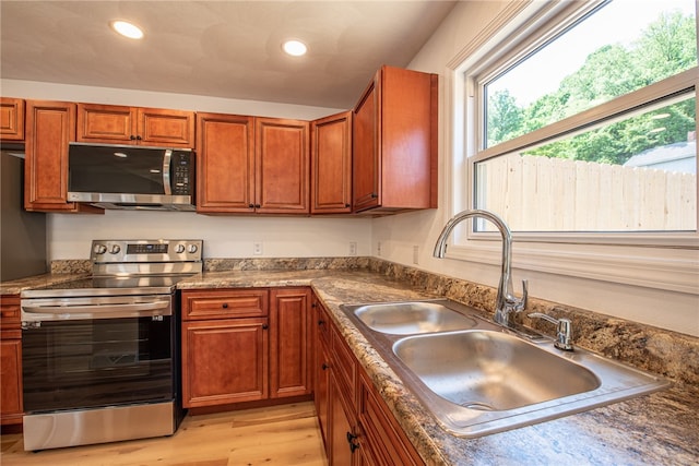 kitchen with stainless steel appliances, sink, and light hardwood / wood-style flooring