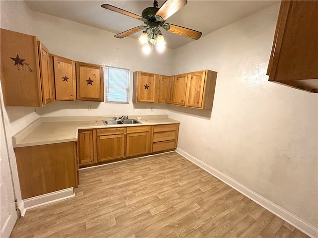 kitchen featuring ceiling fan, sink, and light wood-type flooring