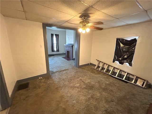 carpeted spare room featuring ceiling fan and a drop ceiling