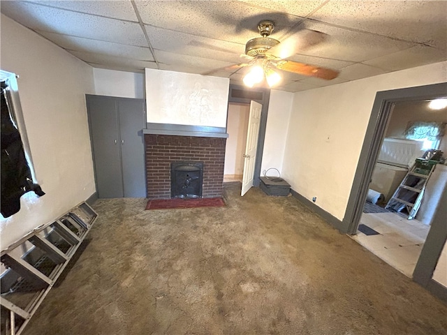 unfurnished living room with carpet flooring, ceiling fan, a fireplace, and a drop ceiling