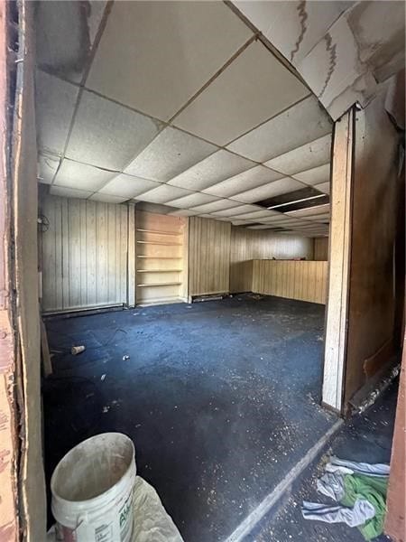 miscellaneous room with wood walls and a drop ceiling