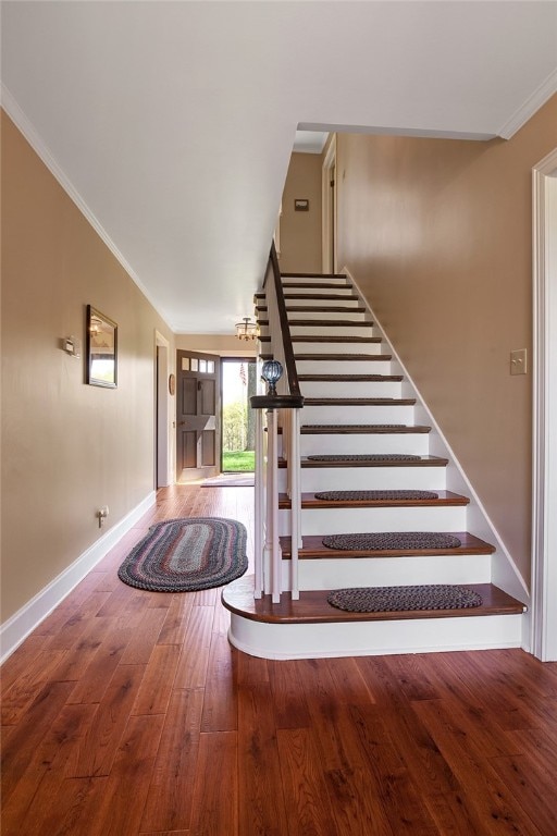 staircase with ornamental molding and hardwood / wood-style floors