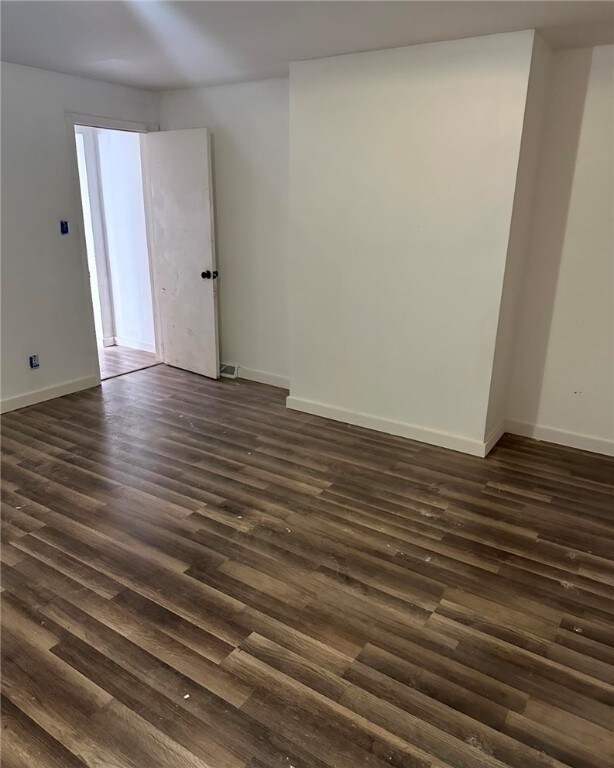 unfurnished room with dark wood-style floors and baseboards