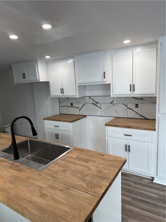 kitchen featuring dark wood-style floors, butcher block counters, a sink, backsplash, and recessed lighting