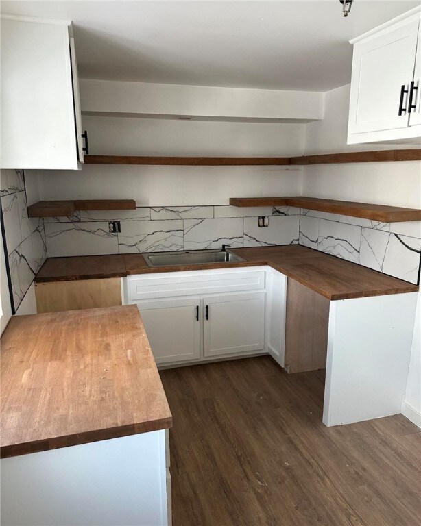 kitchen featuring dark wood-style flooring, white cabinetry, a sink, and open shelves