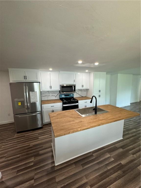 kitchen featuring stainless steel appliances, a sink, wood counters, white cabinets, and dark wood finished floors