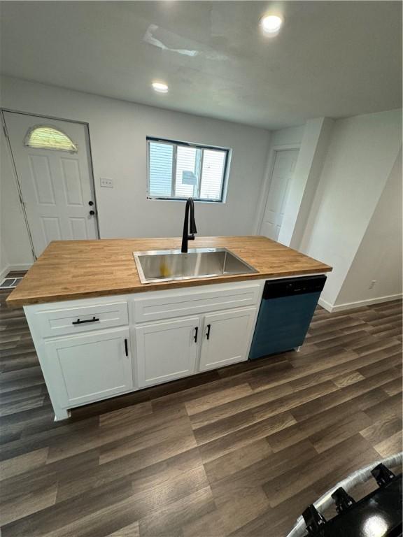 kitchen featuring dishwashing machine, wood counters, dark wood-style flooring, and a sink