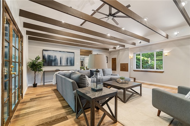 living room featuring beamed ceiling, ceiling fan, and light wood-type flooring