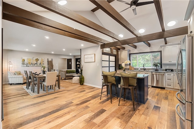 kitchen with light hardwood / wood-style floors, a kitchen breakfast bar, ceiling fan, white cabinets, and appliances with stainless steel finishes