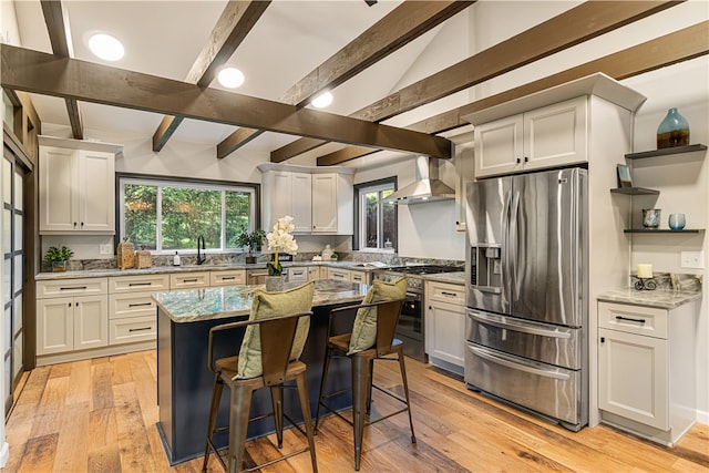 kitchen featuring stainless steel appliances, light stone countertops, lofted ceiling with beams, and light hardwood / wood-style floors