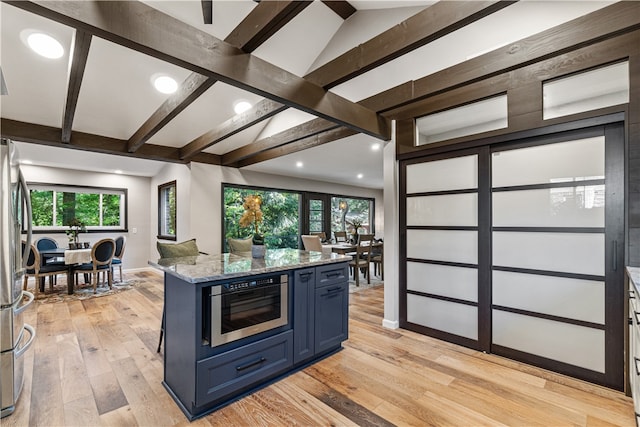 kitchen with blue cabinets, light stone countertops, a healthy amount of sunlight, and light hardwood / wood-style floors