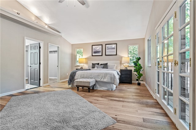 bedroom with multiple windows, ceiling fan, light hardwood / wood-style floors, and lofted ceiling