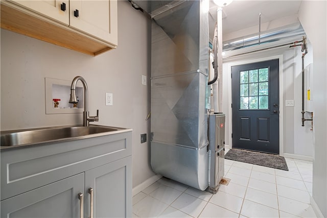 interior space featuring hookup for a washing machine, sink, light tile flooring, and cabinets