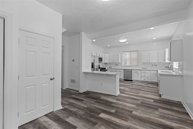 kitchen with stainless steel appliances, dark wood-type flooring, white cabinetry, and tasteful backsplash