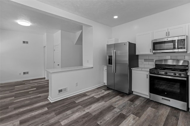 kitchen with white cabinets, dark hardwood / wood-style floors, tasteful backsplash, and stainless steel appliances