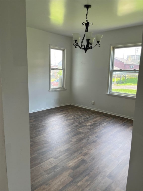 unfurnished room featuring a notable chandelier and dark wood-type flooring