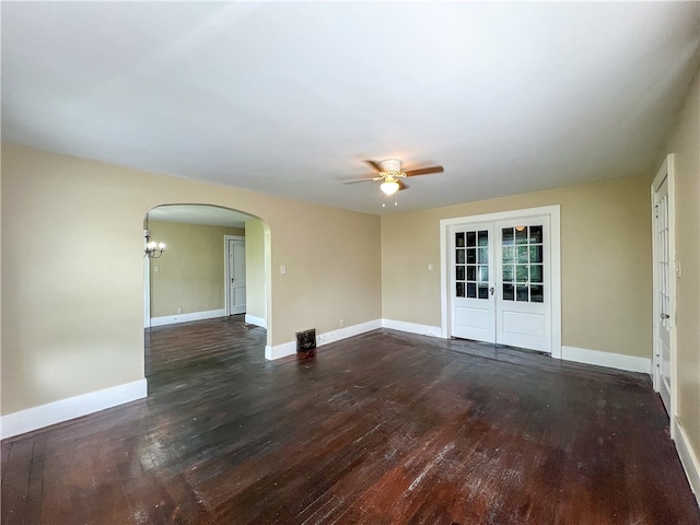 empty room with french doors, ceiling fan with notable chandelier, and dark hardwood / wood-style flooring