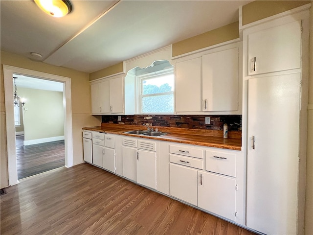 kitchen with wooden counters, wood-type flooring, backsplash, sink, and white cabinetry