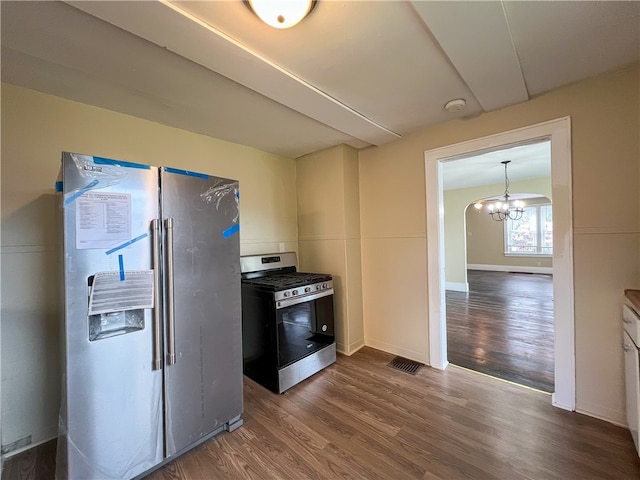 kitchen with appliances with stainless steel finishes, dark hardwood / wood-style floors, and an inviting chandelier